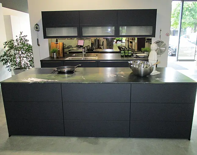 Moderne schwarze Küche mit Kochinsel, Spülbecken, Pfanne, Rührschüssel und großen Fenstern.