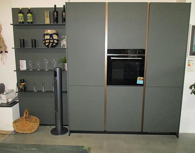 Moderne graue Küche mit eingebautem Backofen, Regalen links mit Deko und Flaschen.