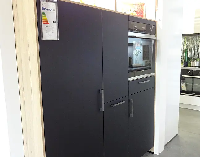 Küchenschrank mit schwarzer Front, eingelassener Ofen und mehreren Griffen.