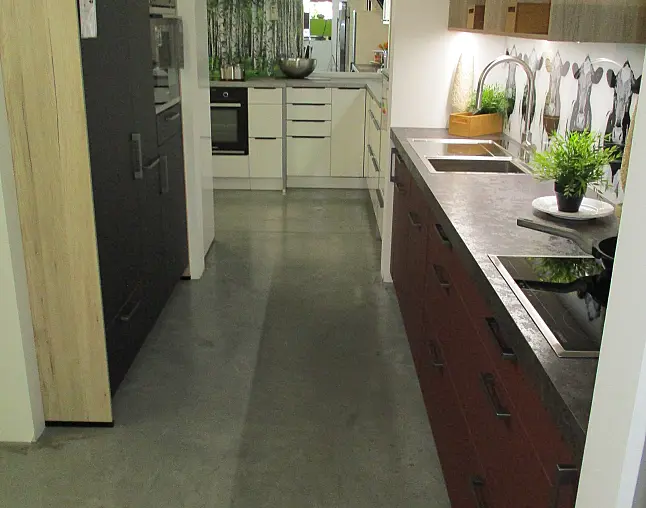 Moderne Küche mit roten und weißen Schränken, grauer Arbeitsplatte und Kuh-Motiv-Fliesenrückwand.