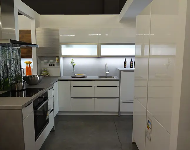 Moderne weiße Küche mit grauer Arbeitsplatte, Herd, Spüle und Hochschränken.