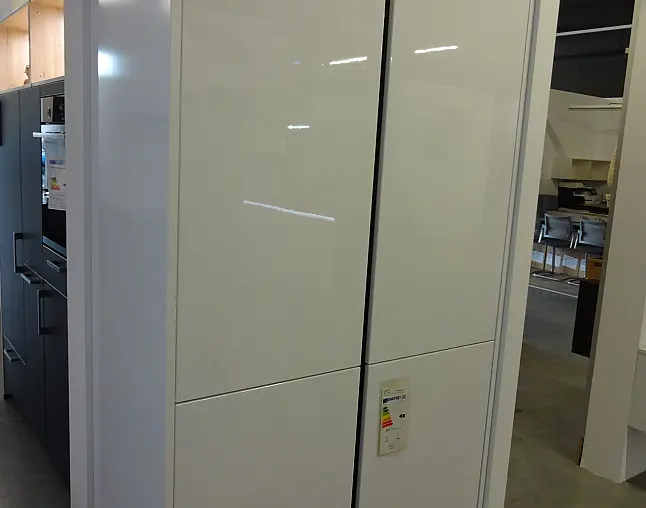 Moderne weiße Küchenschränke mit glänzenden Oberflächen in einem Ausstellungsraum.