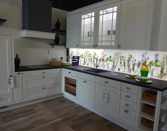 Moderne Küche mit weißen Schränken, eingebautem Ofen, Spüle und Pflanzenbeleuchtung an der Wand.