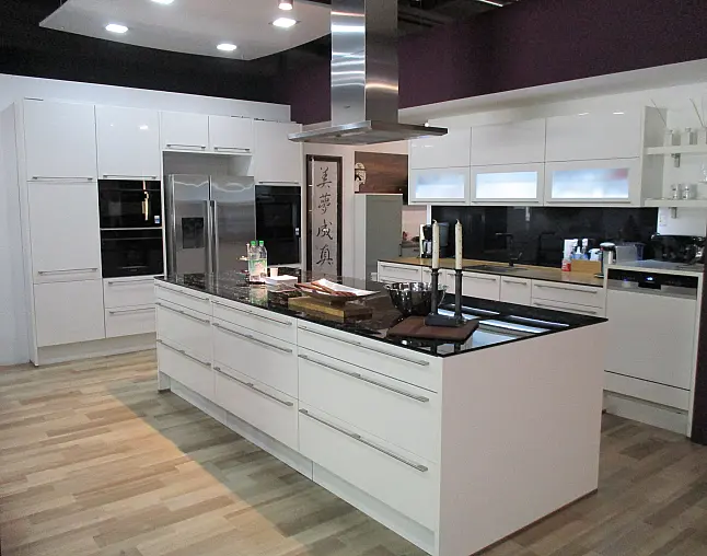 Moderne weiße Küche mit schwarzer Arbeitsplatte, Kücheninsel und Edelstahlgeräten.