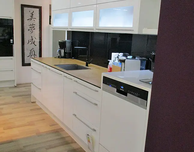 Moderne weiße Küche mit Holzarbeitsplatte, schwarzer Spüle, Kaffeemaschine, Spülmaschine und asiatischem Wandbild.